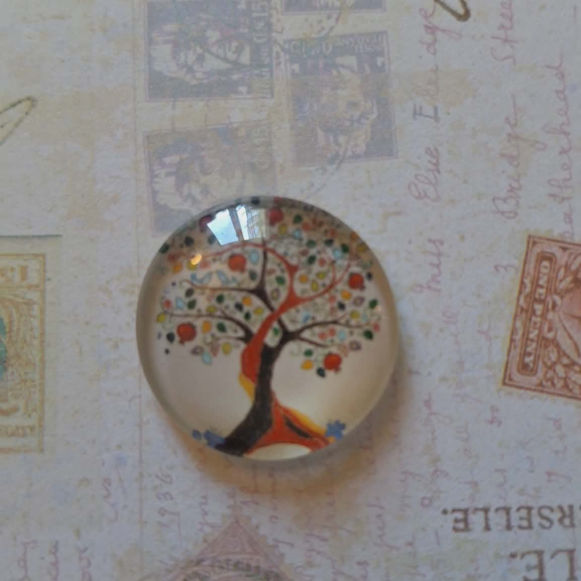 Decorative glass roundel with a tree design on a textured background with stamps and text.