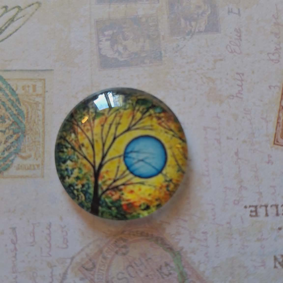 Round decorative item with a tree and moon design on a textured background