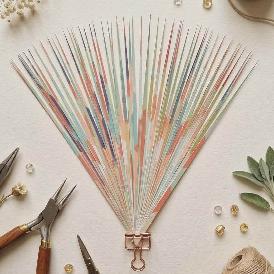 Decorative pre-cut paper strips with colorful rays on a light surface with tools and decorative items.