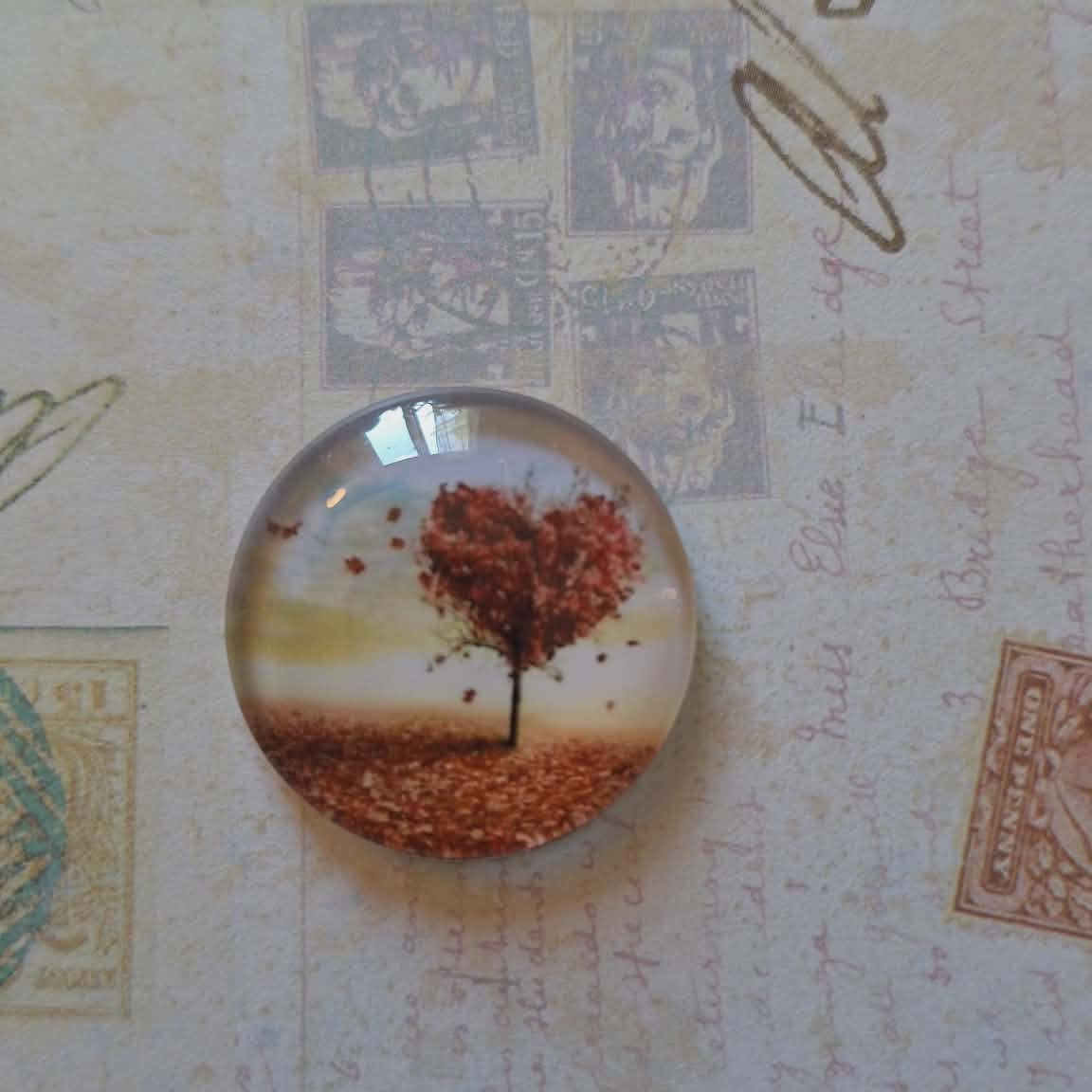 Round glass badge with autumn tree design on a textured background