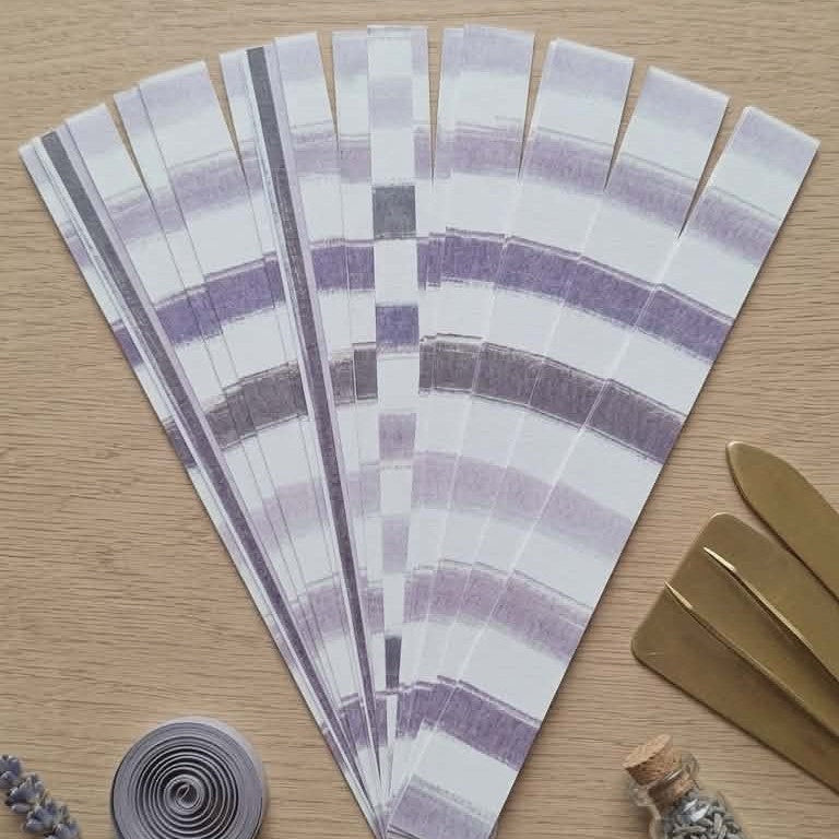 Set of purple striped paper packs on a wooden surface with decorative items.