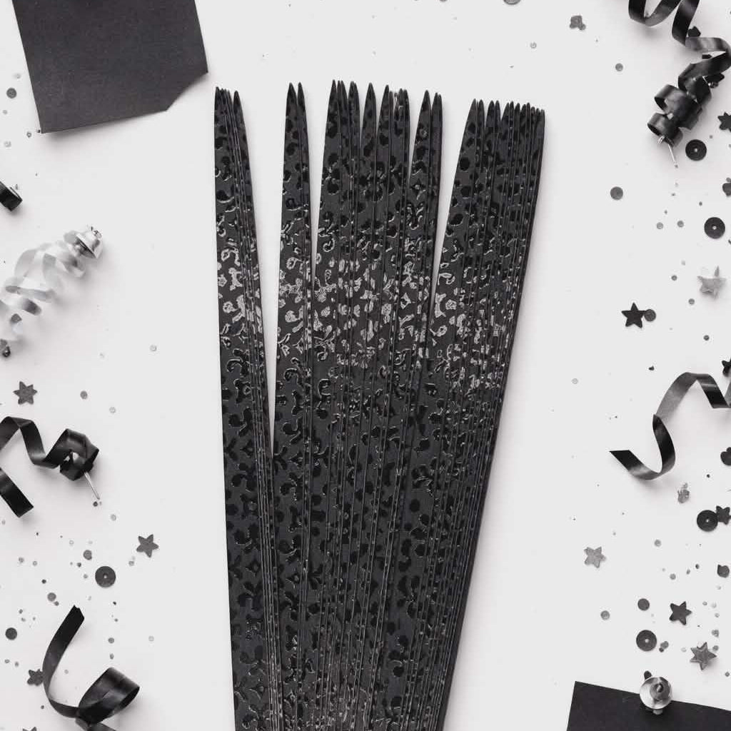 Black decorative ribbons with a textured pattern on a white background with black confetti.
