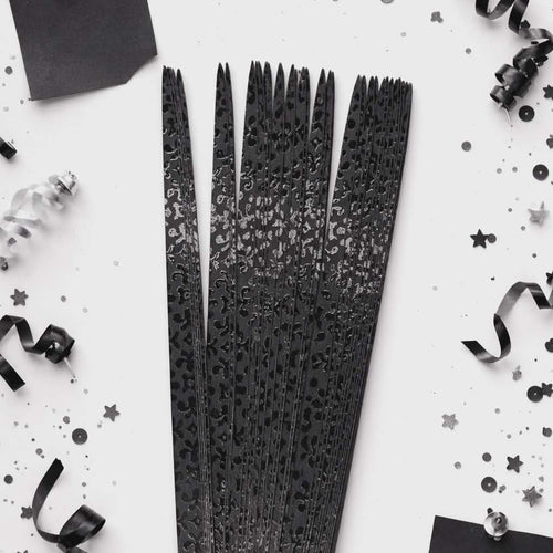 Black decorative ribbons with a textured pattern on a white background with black confetti.