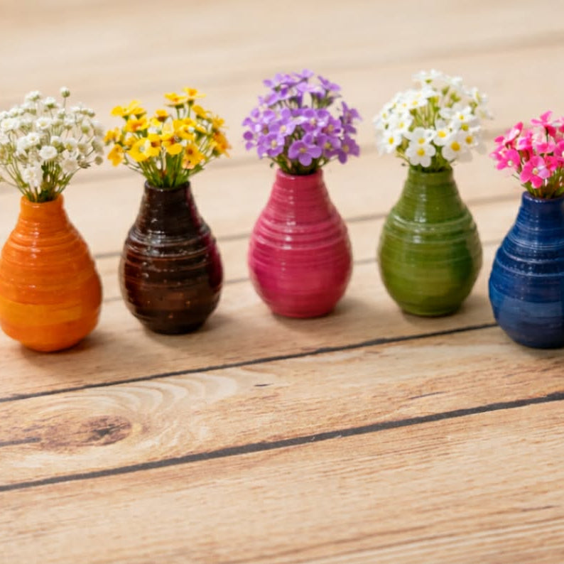 Set of colorful ceramic vases with flowers on a wooden surface