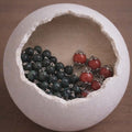 Crimson and olive rosary beads displayed inside a cracked eggshell for DIY Catholic rosary making kit