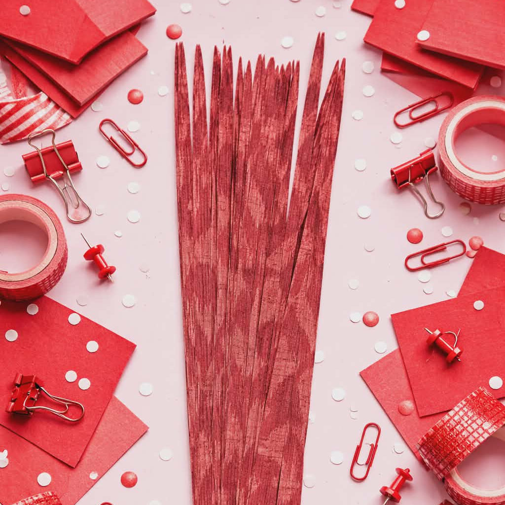 Red paper strips and office supplies on a white background with red polka dots