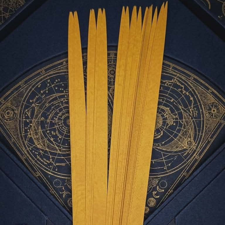 Gold paper bead strips for jewelry making displayed on navy celestial flat lay with crystals and key
