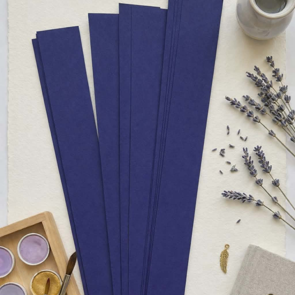Navy blue paper bead strips for rolling handmade paper beads, styled with watercolor paints and lavender for jewelry making and craft projects.