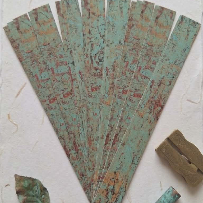 Decorative fan with intricate patterns on a textured surface with leaves and soap.