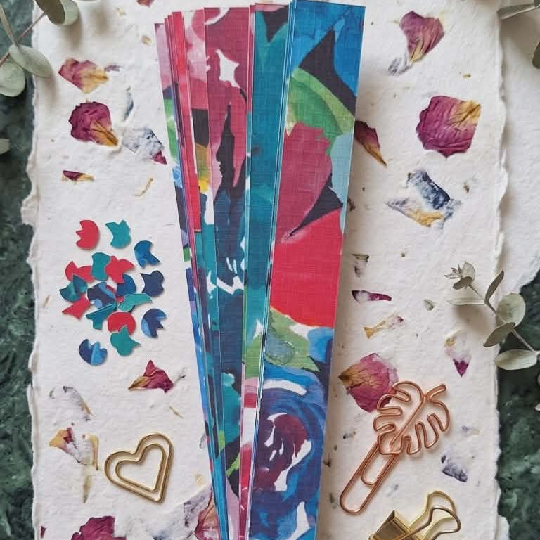 Colorful paper decorative paper clips on a textured surface with floral designs.